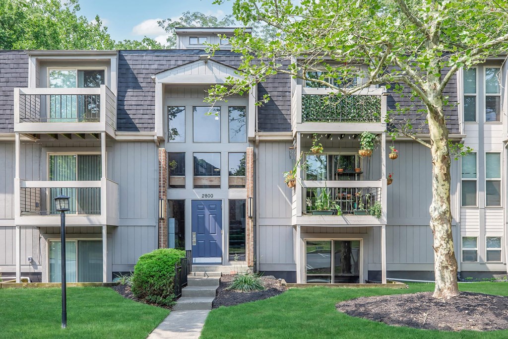 the view of an apartment building with a sidewalk and grass