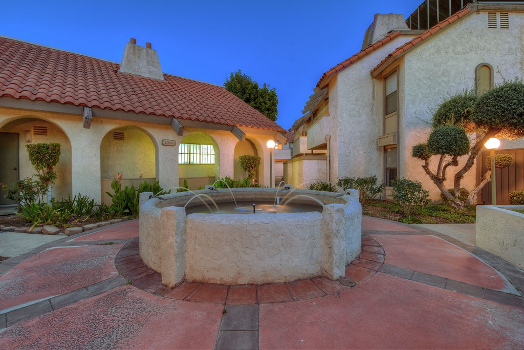 a stone fountain sits in the middle of a courtyard
