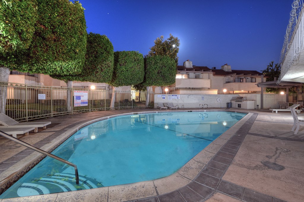 a swimming pool at night at an apartment building with a pool