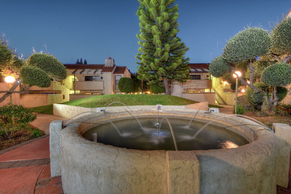 a fountain in a garden in front of a house