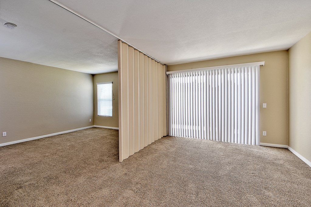 an empty living room with blinds on a window