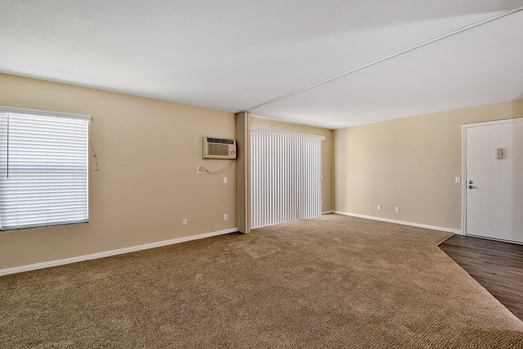 an empty living room with a door to a closet and a window