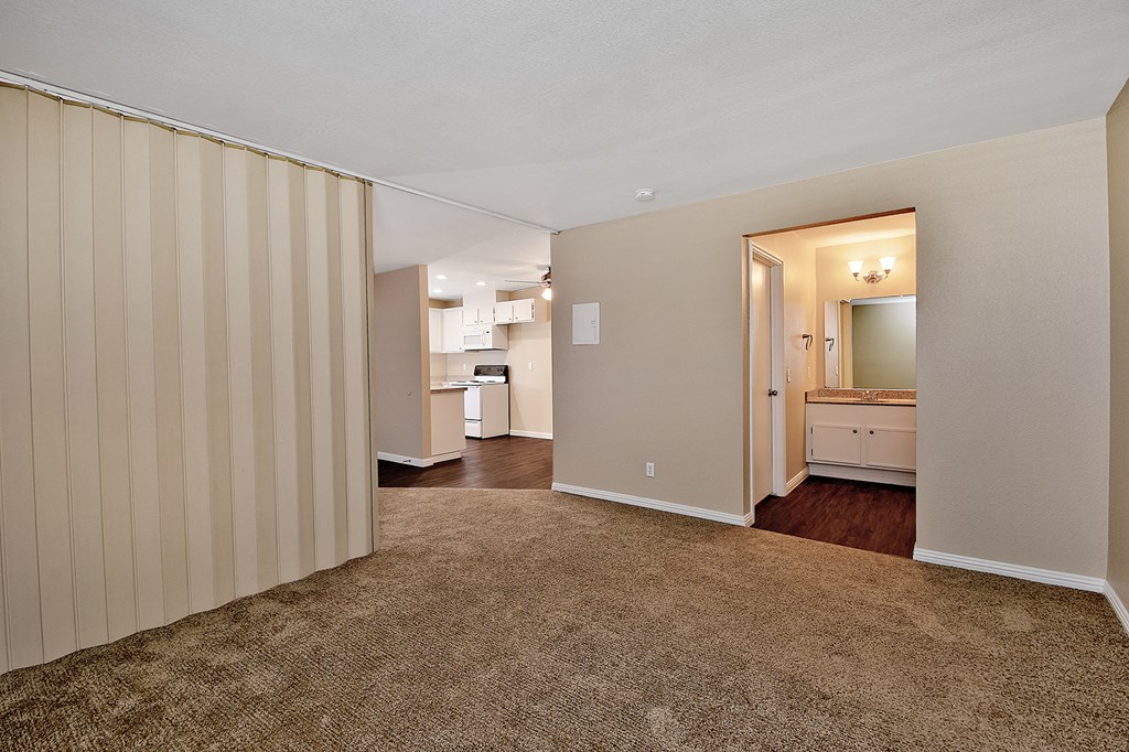 an empty living room with a closet and a kitchen