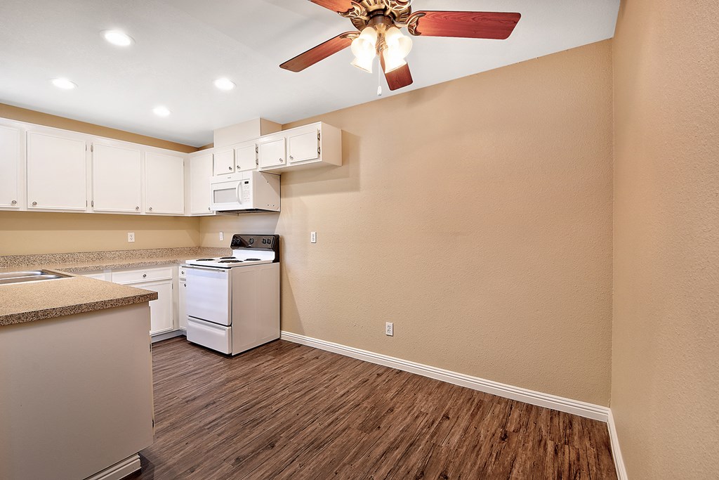 a kitchen with white appliances and a ceiling fan