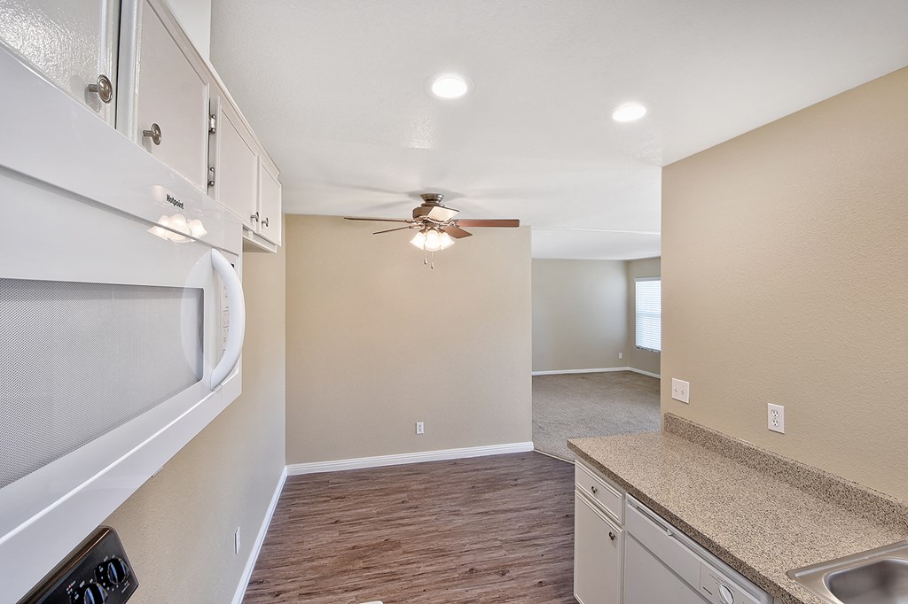 an empty kitchen with white cabinets and a ceiling fan