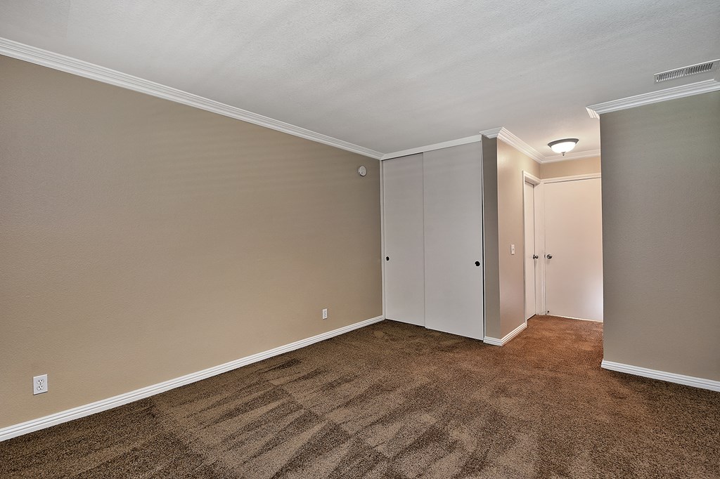 an empty living room with carpet and a door to a hallway