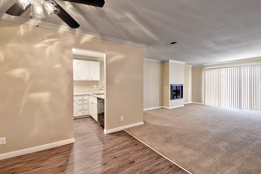 an empty living room and kitchen with a ceiling fan