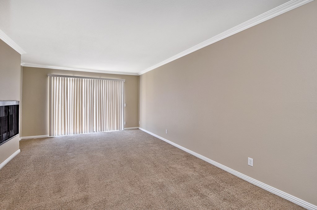 an empty living room with blinds and a window