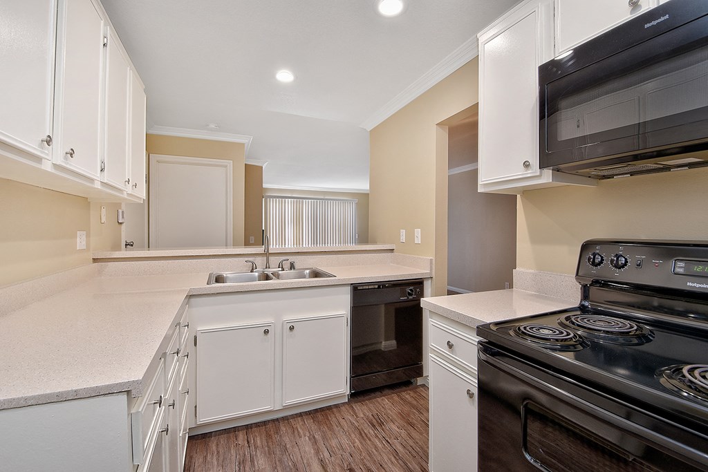 a kitchen with white cabinets and a stove and a sink