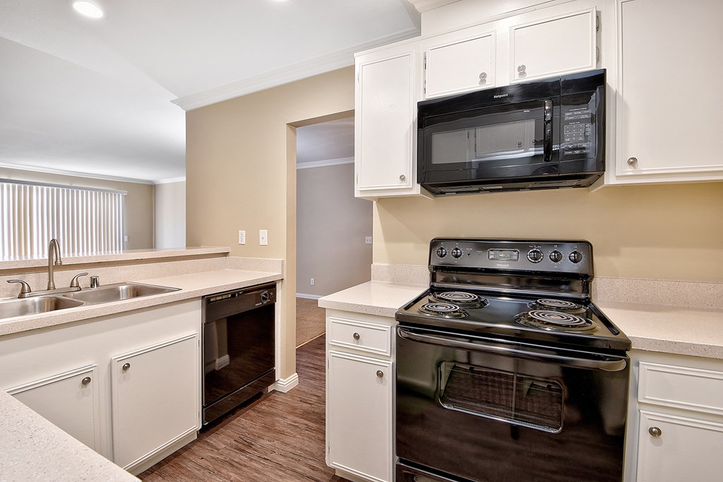 an empty kitchen with a stove microwave and sink