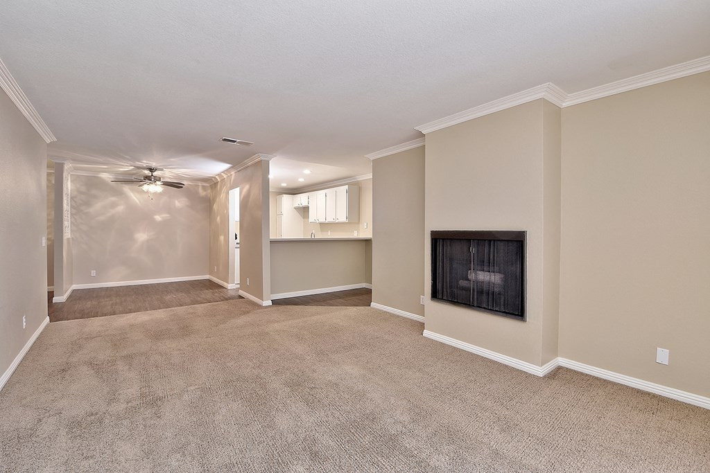an empty living room with a fireplace and a ceiling fan