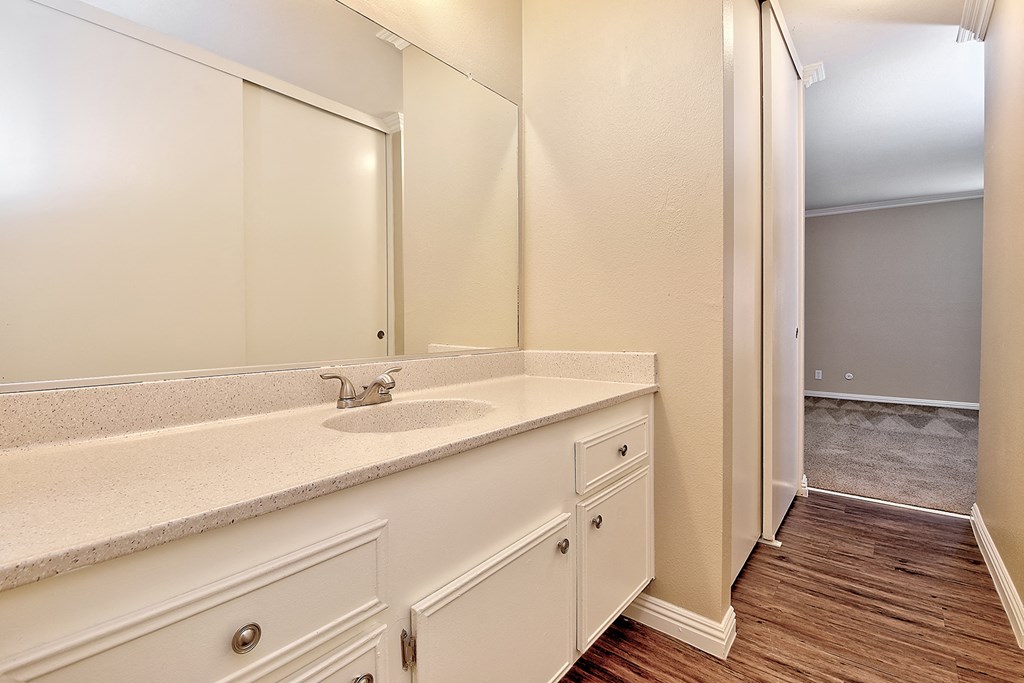 a bathroom with white cabinets and a sink and a mirror