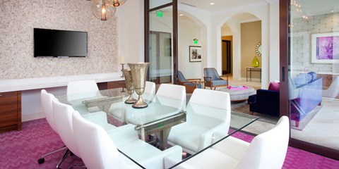 A modern living room with a glass table and white chairs.
