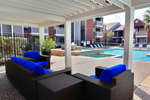 A pool area with a white canopy and blue cushioned seating.