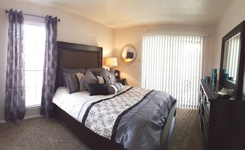 A bedroom with a large bed and a window with curtains.
