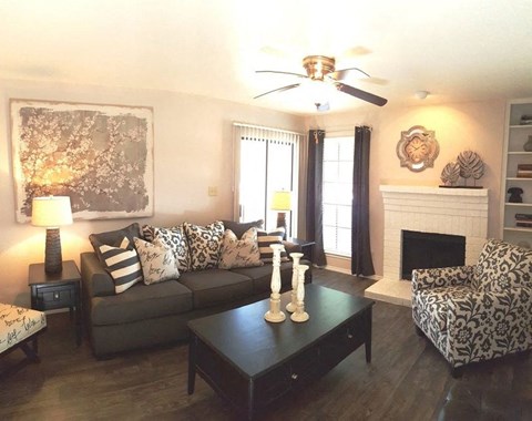 A living room with a grey couch, a black coffee table, and a fireplace.