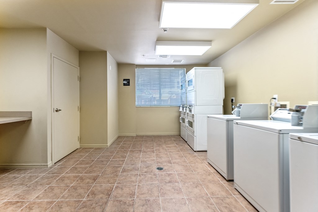 an empty laundry room with washers and dryers and a window