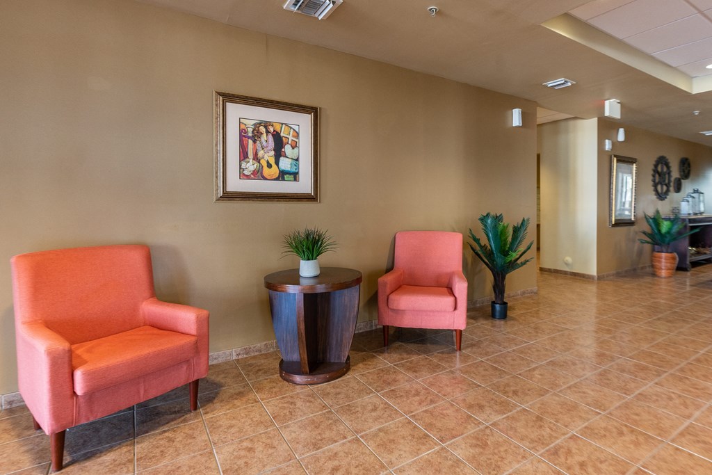 a lobby with two chairs and a table and a hallway with a door