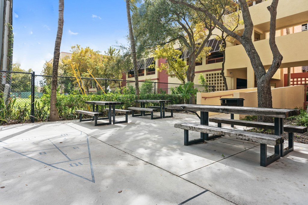 an outdoor patio with picnic tables and a fence
