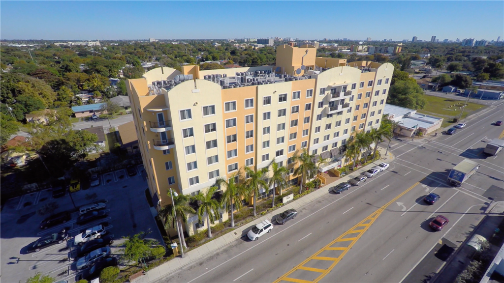 an aerial view of a building with palm trees in front of a street