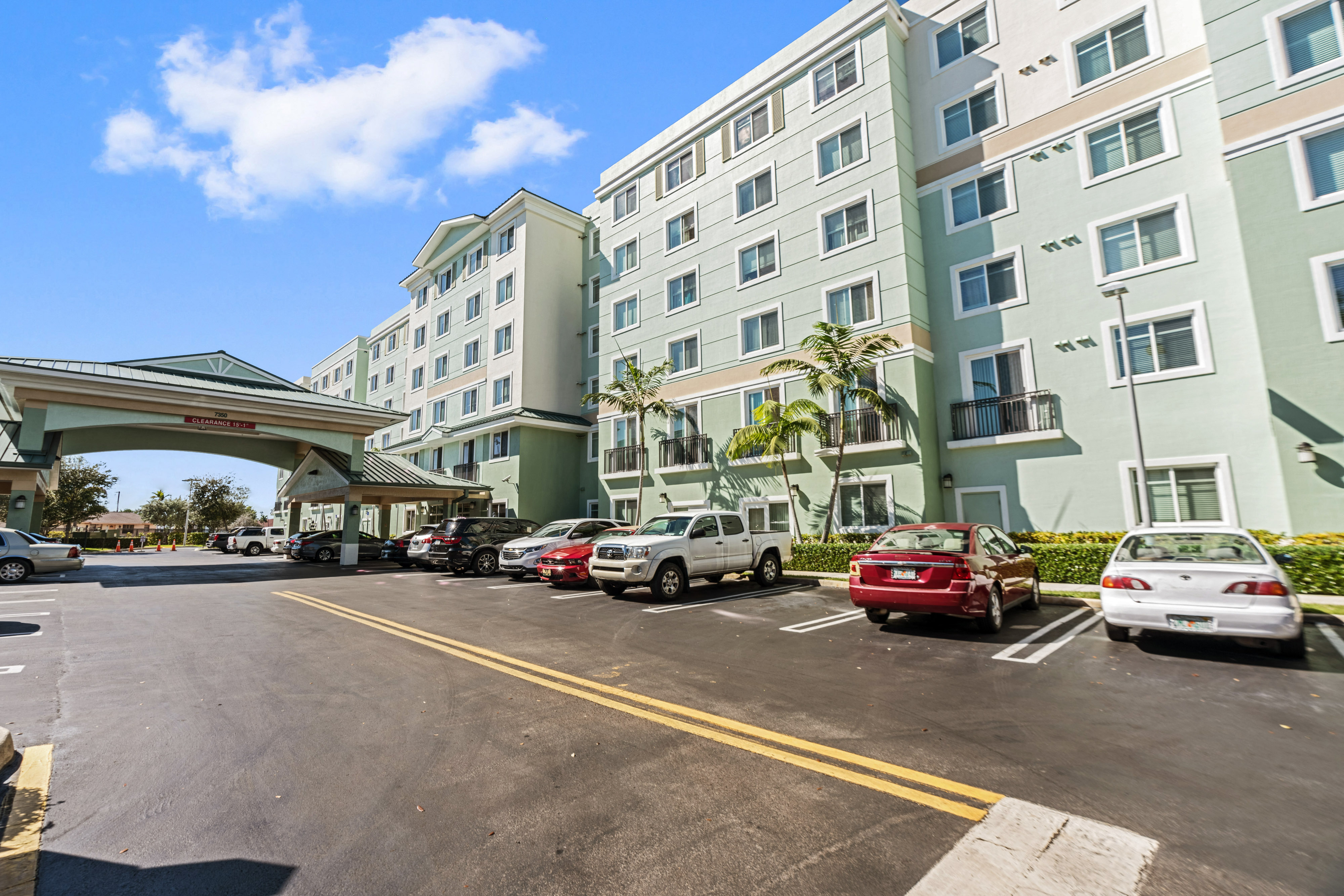 a parking lot in front of an apartment building with cars parked outside