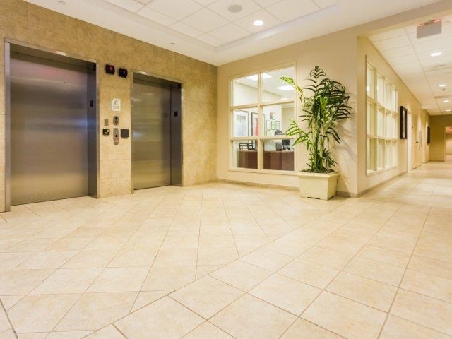 a lobby with two elevators and a potted plant