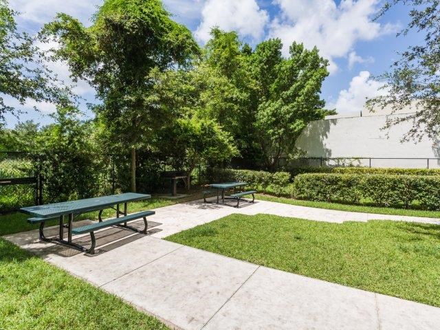 two picnic tables in a park with grass and trees