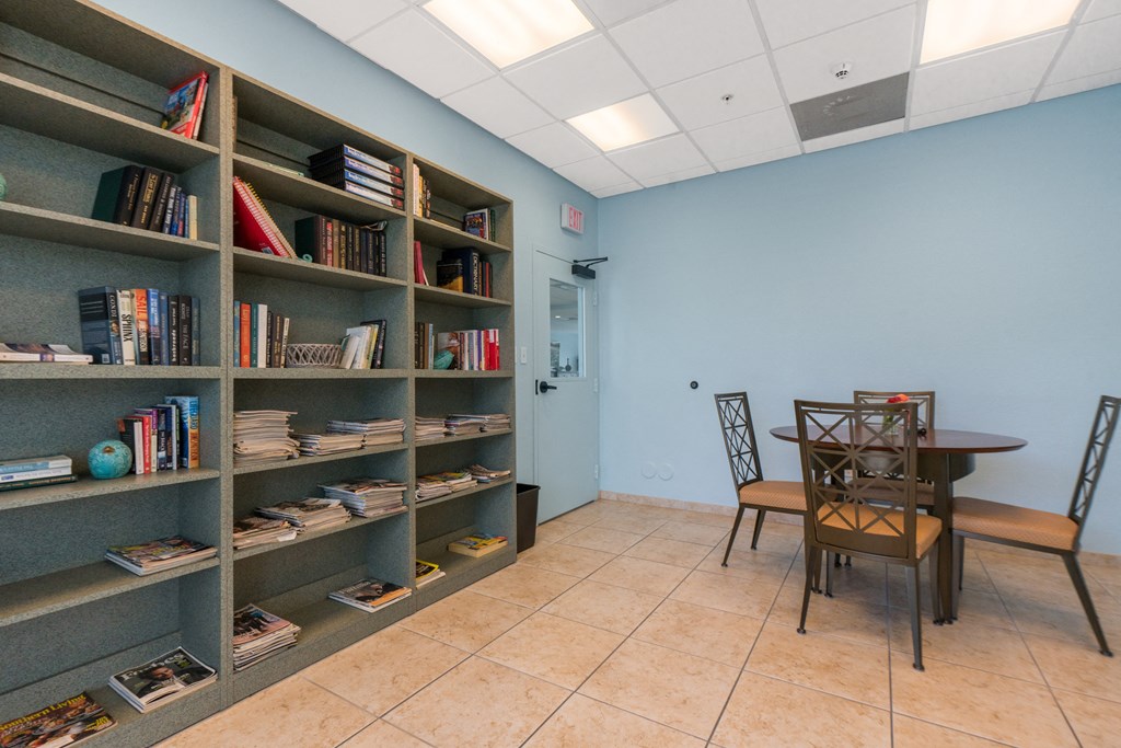 a library with a table and chairs and a bookshelf