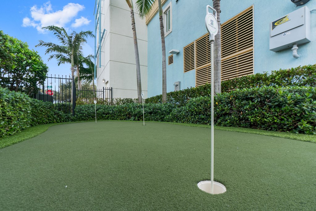 a putting green in front of a building with palm trees