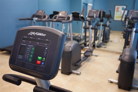 a row of exercise bikes in a gym with other machines