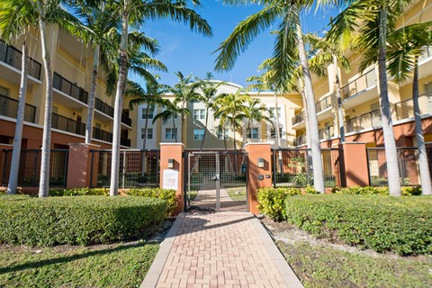 a fenced in area with palm trees in front of a building