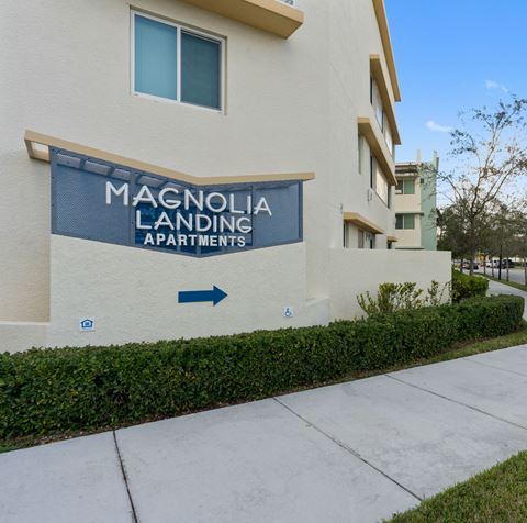 a sidewalk in front of a building with a sign for magnolia landing apartments