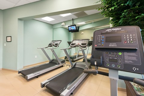 a gym with treadmills and a tv in the corner of a room