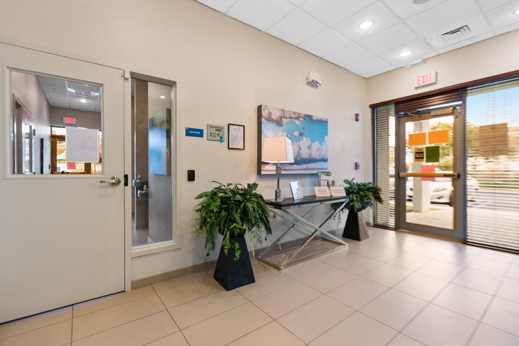a lobby with a glass table and plants in front of a door