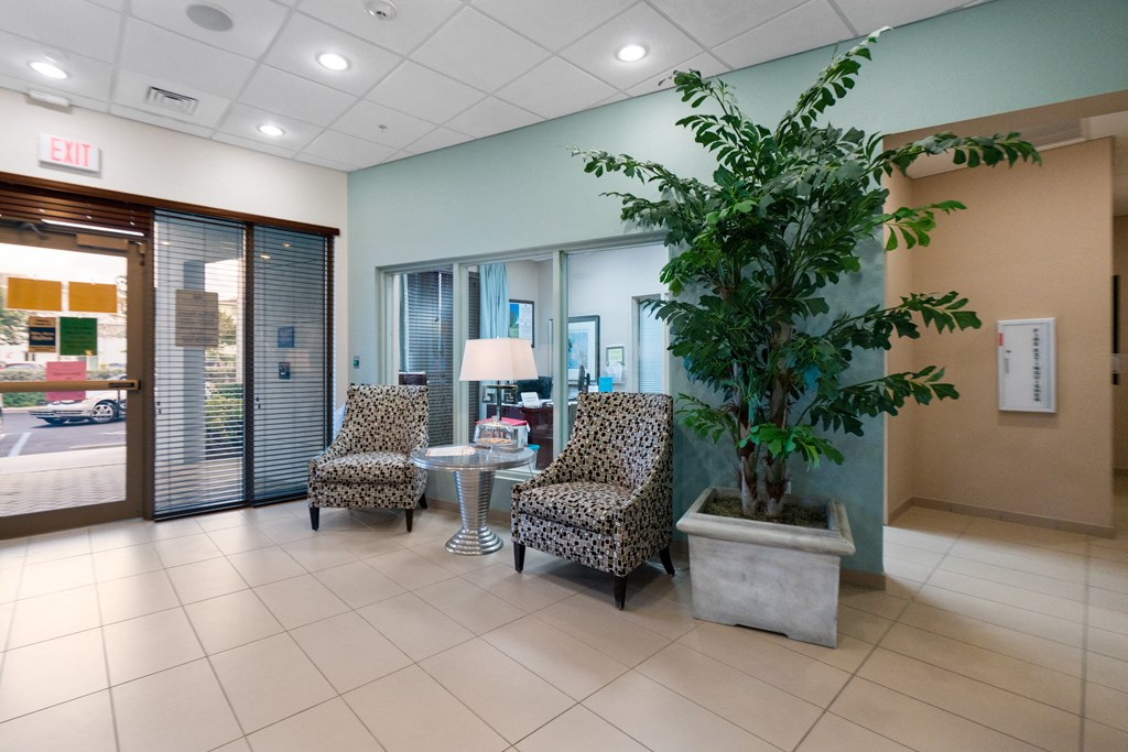 a lobby with chairs and a table and a plant