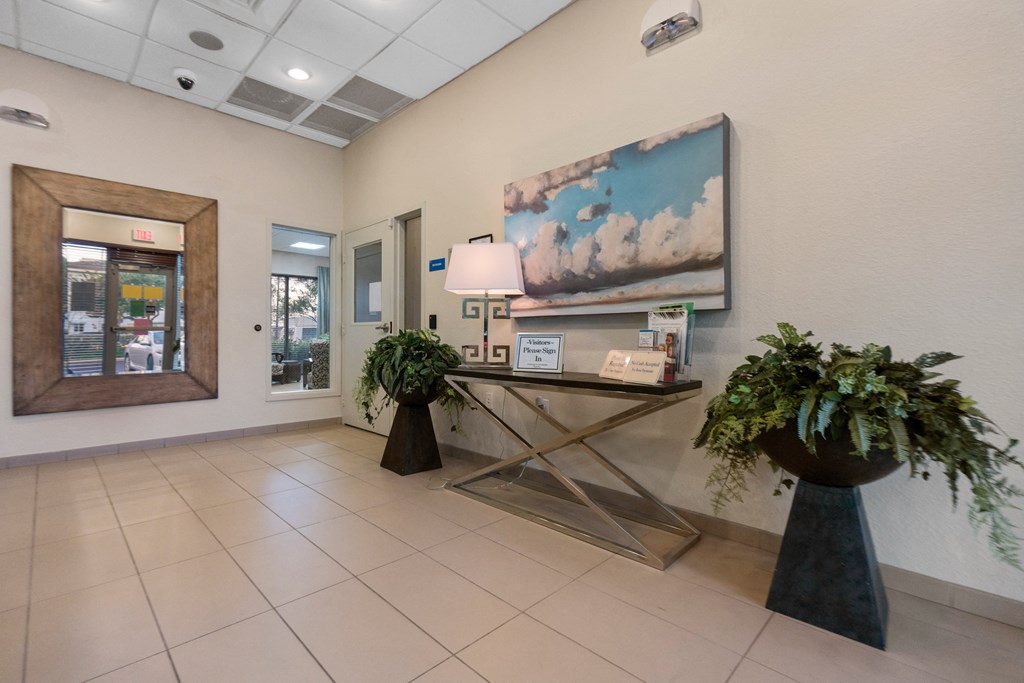 a lobby with plants and a table with a lamp