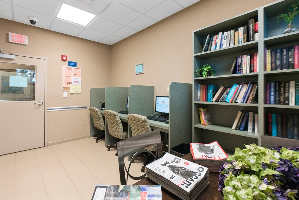 a library with chairs and bookshelves and a desk with a computer