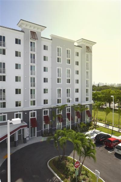 a large white building with palm trees in a parking lot