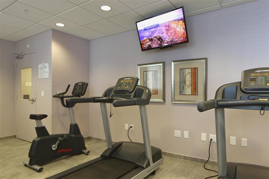 a gym with exercise machines and a tv on the wall
