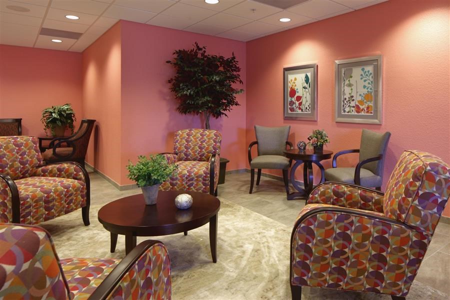 a lobby with chairs and tables and a pink wall