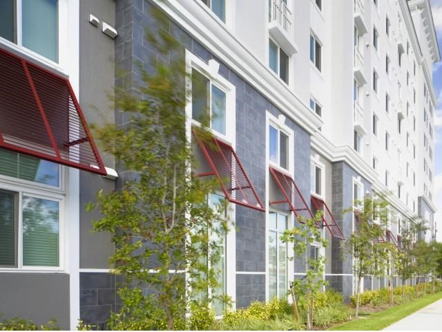 a large building with trees and a sidewalk in front of it