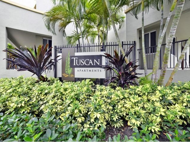 a sign for tuscany apartments in front of a building
