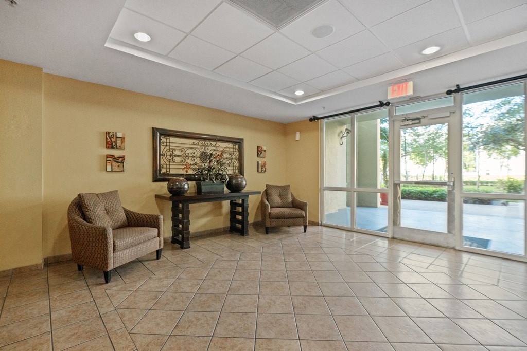 a lobby with chairs and a table in front of glass doors