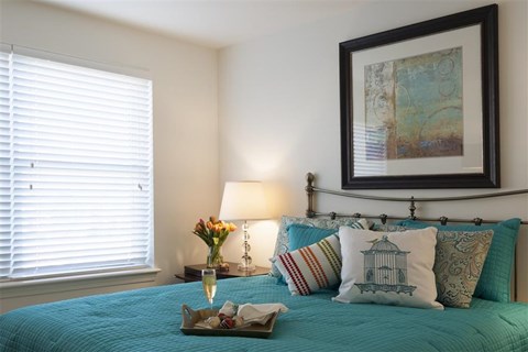 a bedroom with a blue bed and pillows and a window