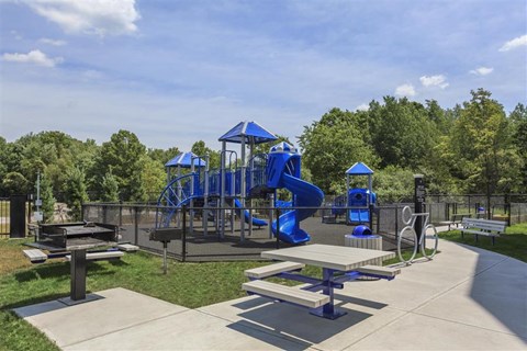a playground with a blue slide and picnic tables