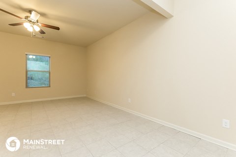 the spacious living room with ceiling fan and tile flooring