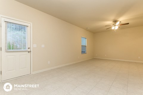 an empty living room with a white door and a ceiling fan