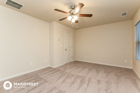 the spacious living room with ceiling fan and carpeted flooring