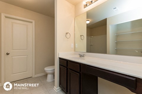 a bathroom with a large mirror and a sink and a toilet