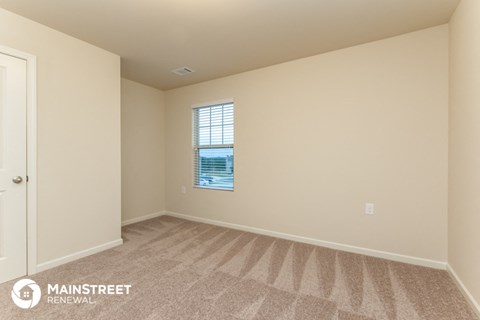 the spacious living room with carpeting and a window